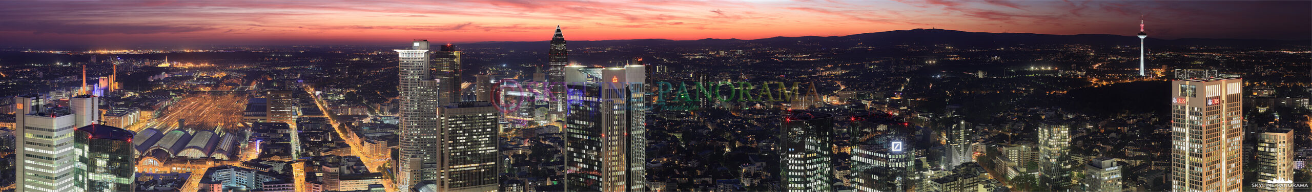 Ein Panorama, das kurz nach dem Sonnenuntergang entstanden ist und den glutroten Himmel über den Bankentürmen der Frankfurter City zeigt - der Ausblick geht in Richtung Westen, über den Hauptbahnhof, die Frankfurter Messe bis hinauf in den Taunus mit dessen höchster Erhebung, dem Feldberg. 