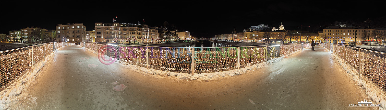 Bilder aus Österreich - Panoramablick vom weihnachtlich geschmückten Makartsteg über die Salzach in Salzburg, die Aufnahme wurde am Abend erstellt.