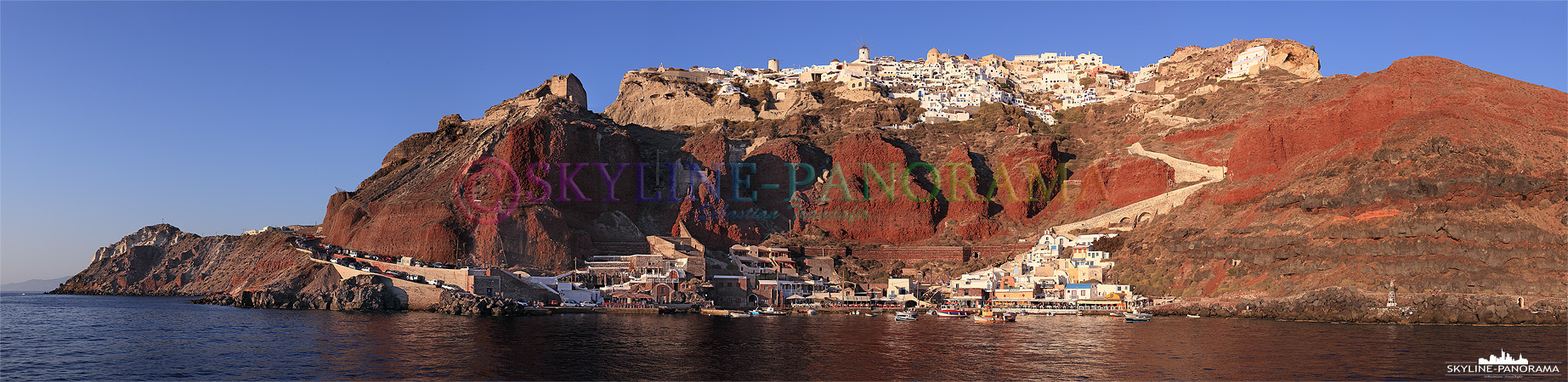 Steilküste von Santorini mit Hafen Ammoudi, der sich unterhalb von Oia befindet. Das Panorama entstand von einem Ausflugsboot aus und zeigt den Felsen von Oia