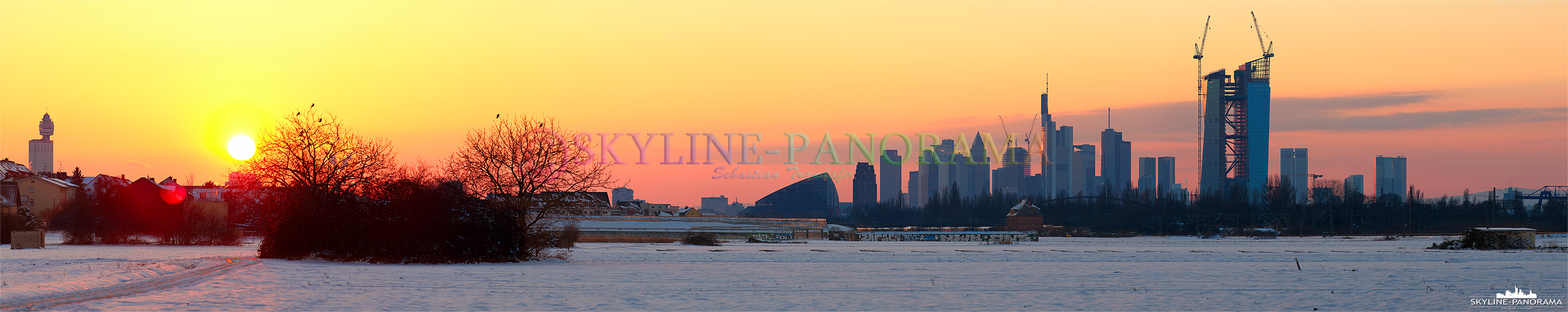 Sonnenuntergang Frankfurt - Die verschneite Frankfurter Skyline von dem im Osten gelegenen Stadtteil Oberrad aus gesehen. Das Panorama entstand kurz vor Sonnenuntergang im Frühjahr 2013 und zeigt die Skyline mit den bekannten Wolkenkratzern, dem Henninger Turm, sowie dem Neubau der Europäischen Zentralbank. 