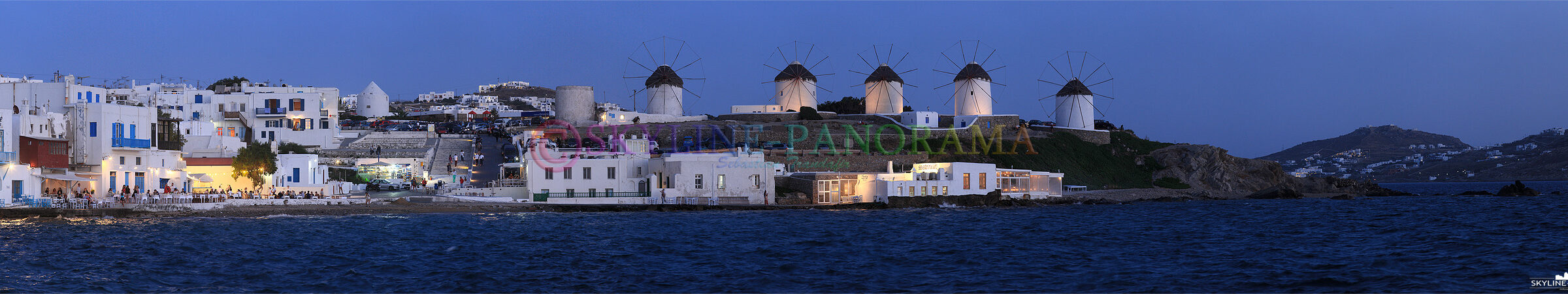 Die als Kato Myli bekannten 5 Windmühlen von Mykonos sind nach Sonnenuntergang zu sehen, Restaurants im Alefkandra Viertel bewirten ihre Gäste direkt am Wasser