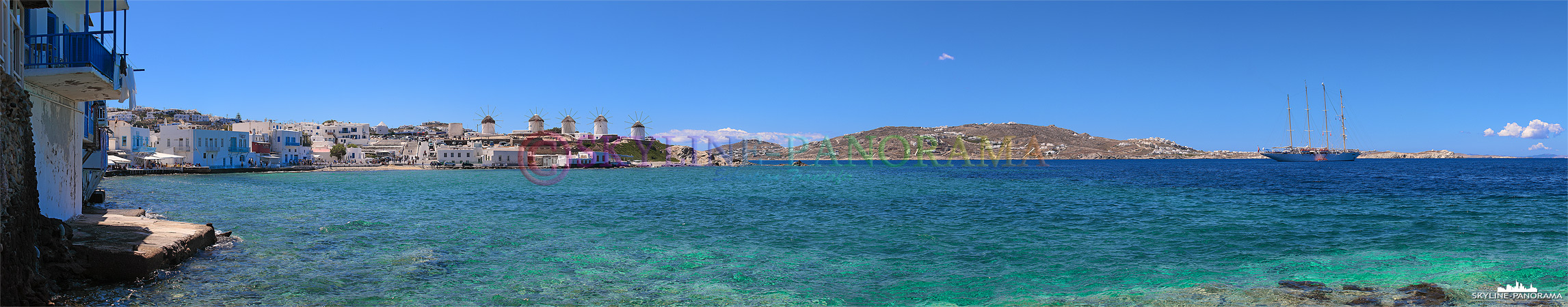 Panorama vom Kastro-Viertel aus auf die Bucht von Alefkandra, zu sehen sind die bekannten Windmühlen von Mykonos und ein vor der Insel ankerndes Segelschiff.