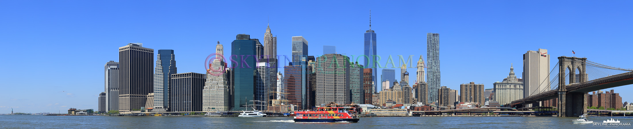 Skyline von Manhattan - Dieses Panorama entstand am Tag, vom Brooklyn Bridge Park im New Yorker Stadtteil Brooklyn, es zeigt die Südspitze von Manhattan, auch als Finanzdistrikt bezeichnet, mit der Brooklyn Bridge, dem One World Trade Center 1 und am linken Bildrand - relativ klein - die Freiheitsstatue. 