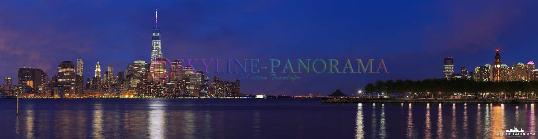 Bilder New York - Die hell erleuchtete Skyline von Lower Manhattan in der Dämmerung mit dem Financial District und einem Teil der Pieranlagen von Hoboken, New Jersey.