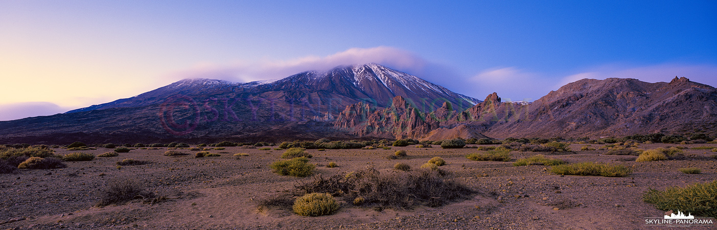 Zur Dämmerung unterwegs auf dem Teide Plateau. Der schneebedeckte Gipfel des El Teide leuchtet bei diesem Panorama im letzten Licht der untergehenden Sonne.