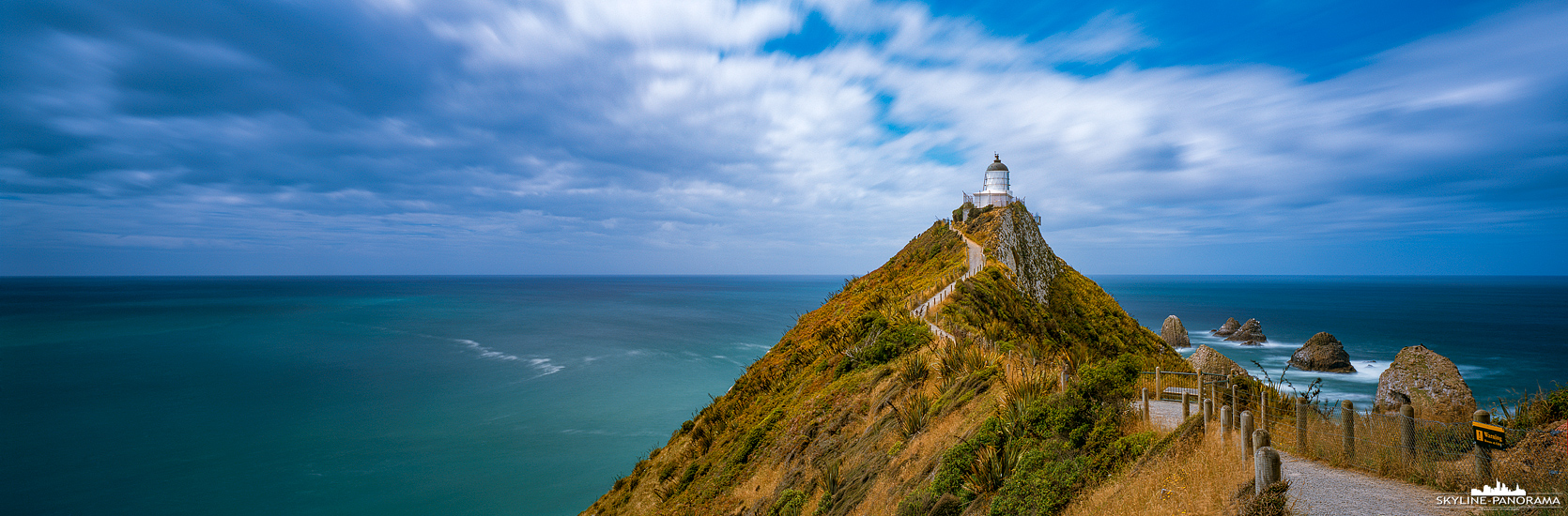 Südinsel Neuseeland - Ein lohnenswerter Abstecher, auf dem Weg von Dunedin zum Lake Te Anau, war der Leuchtturm am Nugget Point in der Region Otago auf der Südinsel von Neuseeland. Zum Leuchtturm führt, vom Parklatz aus, ein ca. 1km langer Weg, den man gut für eine kleine Wanderung nutzen kann. Dieses Panorama ist eine Langzeitbelichtung im Format 6x17. Durch die Verwendung eines ND Filters kann man die Belichtungszeit um ein Vielfaches verlängern, wodurch beispielsweise die Bewegung der ziehenden Wolken sichtbar wird. Das man dies in nur einer Aufnahme festhalten kann, ist der große Vorteil einer echten Panoramakamera.