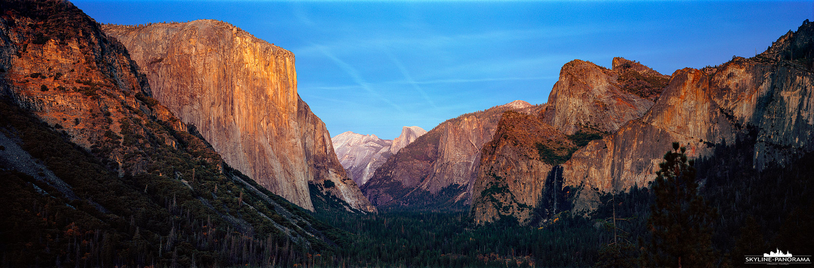 6x17 Panorama USA - Ein Ausblick zum Sonnenuntergang in das beeindruckende Valley des Yosemite National Park von einem der beliebtesten Aussichtspunkte aus, dem Tunnel View Poin. Die Letzten Sonnenstrahlen erleuchten die beiden bekanntesten Gipfel des Yosemite Nationalparks, rechts den El Capitan, mit seiner fast 1000 Meter hohen Felswand und dem Halfdome, am anderen Ende des Yosemite-Tals.