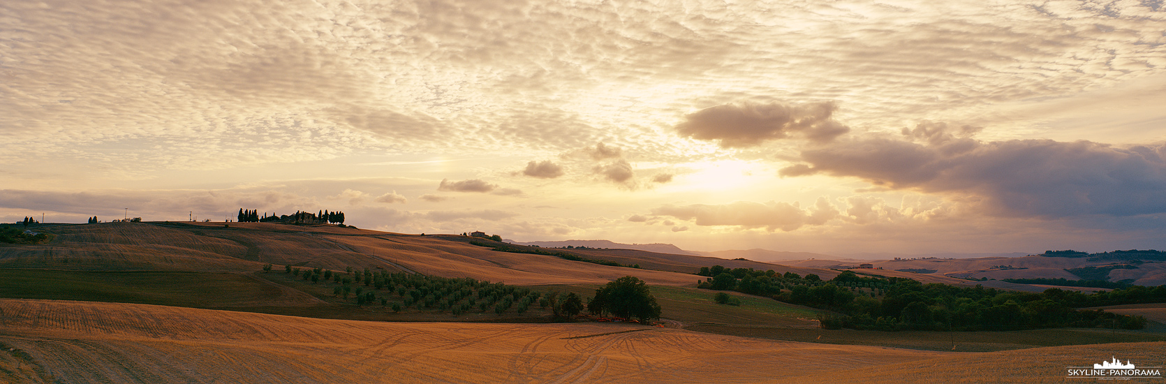 Die malerische, sanft hügelige Landschaft der italienischen Region Toskana als Panorama kurz vor Sonnenuntergang.