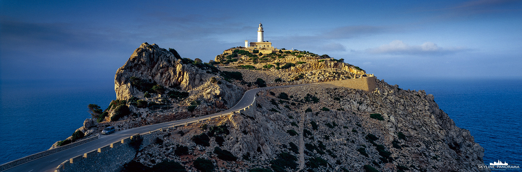 Bilder aus Mallorca - Der Leuchtturm am Cap de Formentor ist eines der bekanntesten Landmarken der Insel Mallorca, bereits beim Anflug mit dem Flugzeug kann man die Felsspitze mit dem beeindruckenden Seezeichen erkennen. Das Cap de Formentor liegt im Nordwesten der Ferieninsel, am nördlichen Ende der Serra de Tramuntana und ist durch eine gut ausgebaute Zufahrtsstraße sicher mit dem Auto erreichbar. Hier zu sehen ist der Leuchtturm als 6x17 Panorama im letzten Licht der untergehenden Sonne.