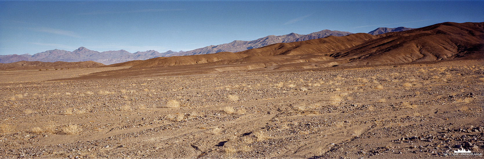 Die steinige und oft als lebensfeindlich bezeichnete, weite Landschaft des Death Valley, bietet für Fotografen spannende Perspektiven. In diesem Panorama, welches in der Ebene des Valleys entstanden ist, sind in der Ferne die umliegenden Höhenzüge der Grapevine Mountains zu sehen.