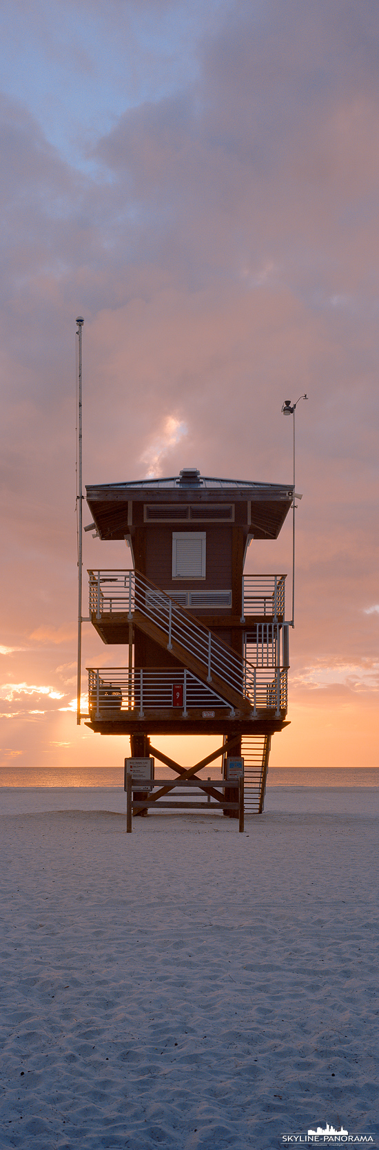 6x17 vertikal Panorama - Ein Rettungsschwimmerturm am Coquina Beach von Bradenton Beach an der Westküste von Florida zum Sonnenuntergang im November 2021.