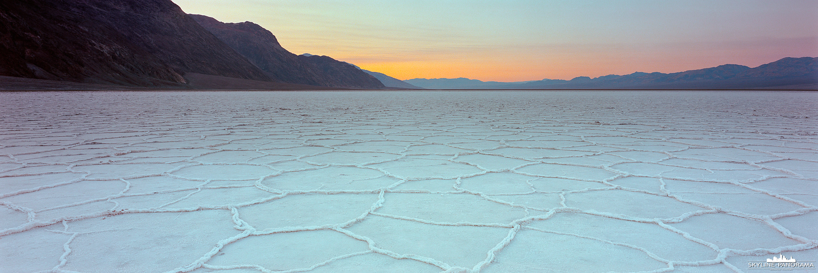 Sonnenuntergang am Bad Water Basin im Death Valley Nationalpark, die Stelle ist bekannt dafür, dass sie der tiefste Punkt Nordamerikas ist. Außerdem empfiehlt es sich vom Besucherparkplatz aus eine kleine Wanderung auf die große Salzfläche, mit den beeindruckenden Strukturen aus Salzkristallen, zu unternehmen. Mit zunehmender Entfernung vom hektischen Treiben in unmittelbarer Nähe zum Parkplatz, nimmt die Stille an diesem magischen Ort zu. Befindet man sich cirka 1 - 2 Meilen auf der Ebene, kann man die absolute Geräuschlosigkeit genießen, natürlich nur, wenn man sich nicht bewegt und die Salzkristalle unter den Schuhsohlen aufhören zu knirschen. 