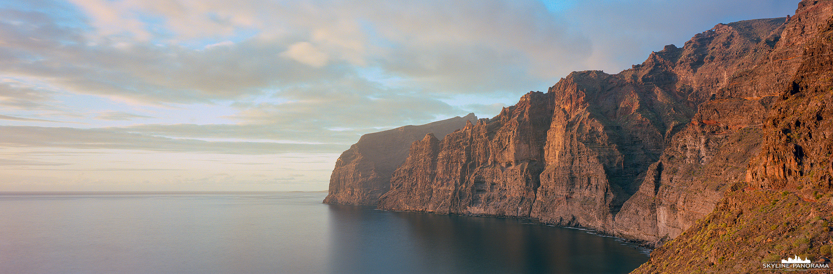 Sehenswertes auf der Ferieninsel Teneriffa - Die Klippen von Los Gigantes in Santiago del Teide leuchten in diesem Panorama goldgelb zum Sonnenuntergang. 