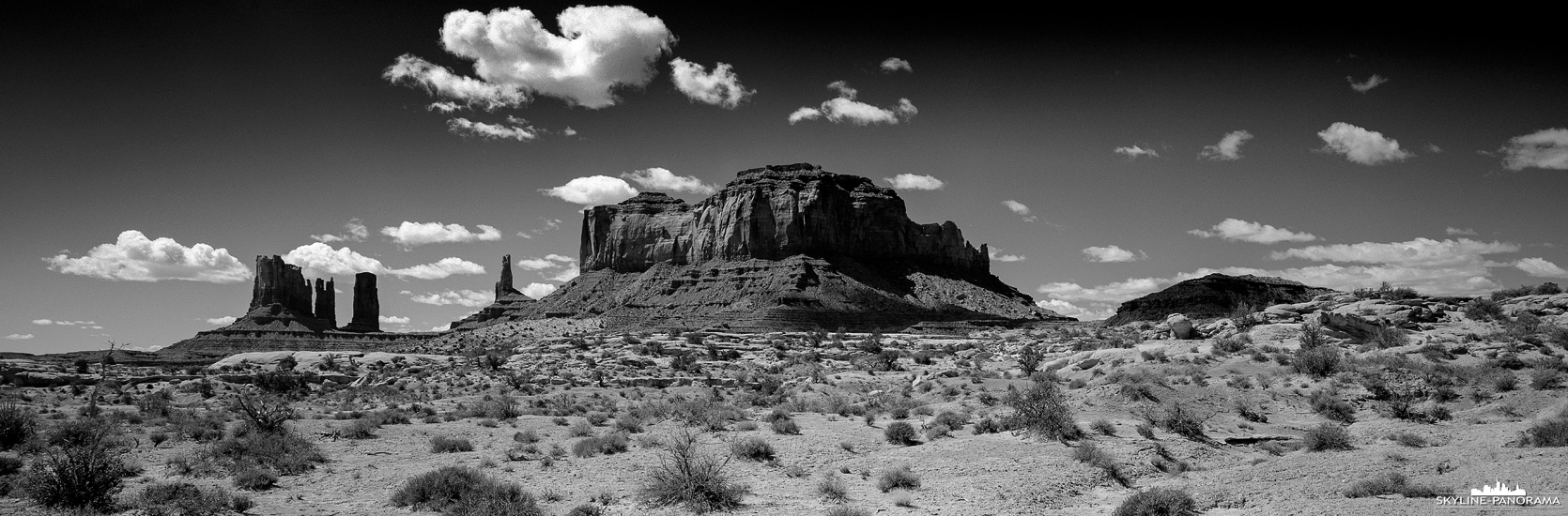 Monument Valley - Arizona / Utah in 6x17 (p_01301) Monument Valley in Schwarzweiß - Dieses analoge Panorama in Filmformat von 6x17 entstand entlang der U.S. Route 163 im Gebiet des Monument Valley. Die markanten Sandsteinformationen der Navajo Nation erheben sich majestätisch aus der weiten Landschaft des amerikanischen Südwestens, die Monolithen und Tafelberge sind bis zu 300 Meter hohen.
